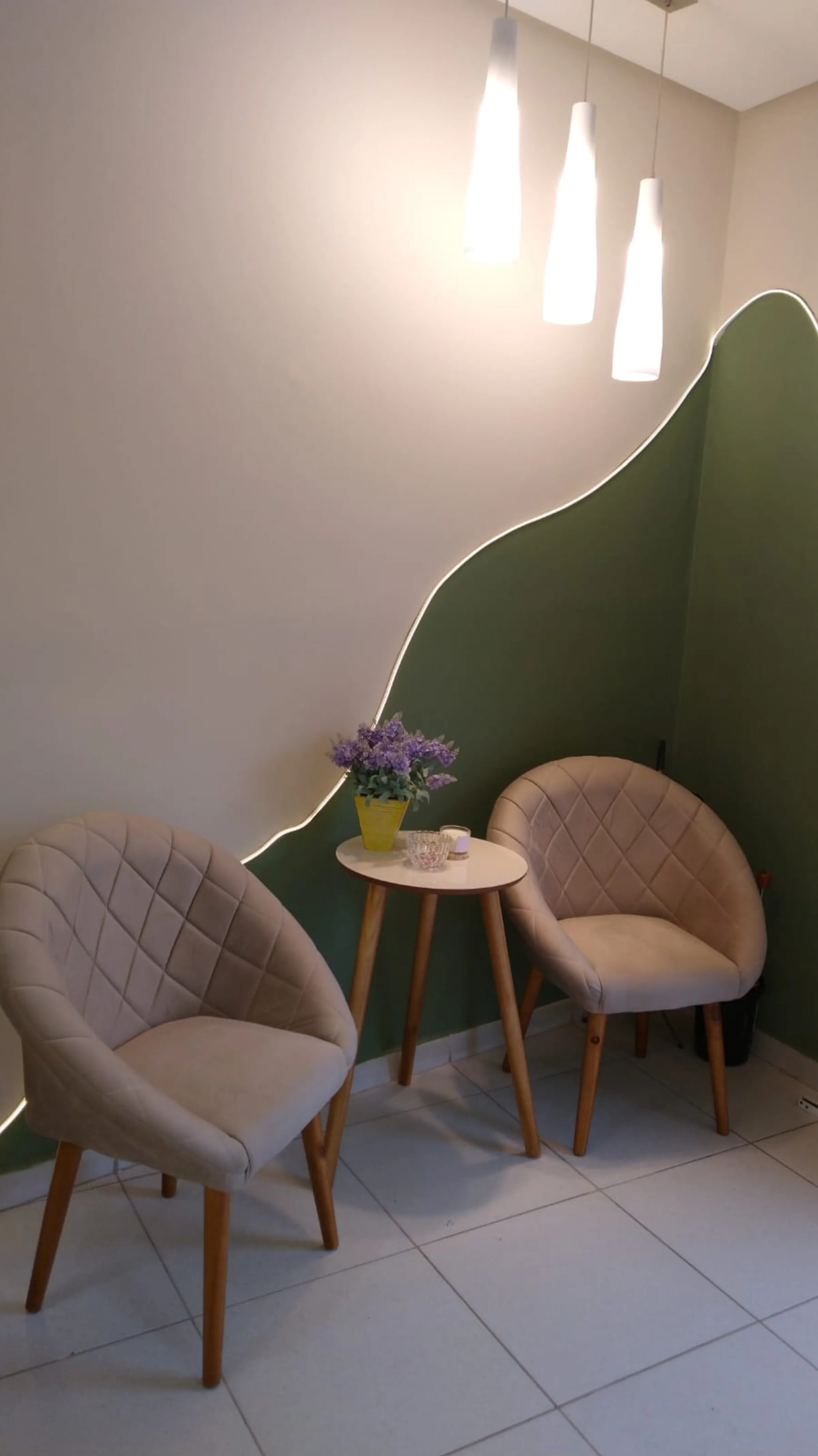 Interior da Santos Estética: parede verde organica sobre areia, luz natural